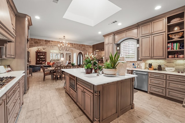 4309 Greenville Dr, Midland, TX 79705 - kitchen featuring stainless steel appliances, a chandelier, a center island with sink, light countertops, and ornamental molding