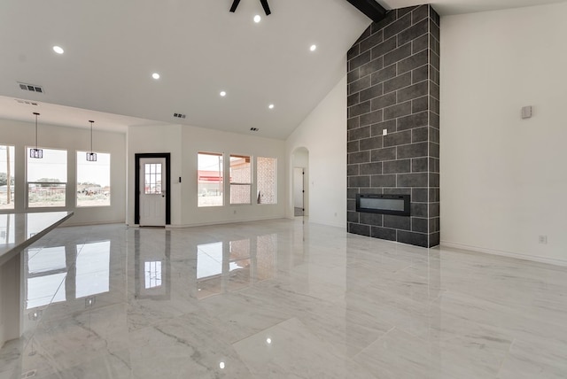12045 W Palomino Ave, Odessa, TX 79764 - unfurnished living room featuring light marble finish flooring, high vaulted ceiling, a tile fireplace, arched walkways, and recessed lighting