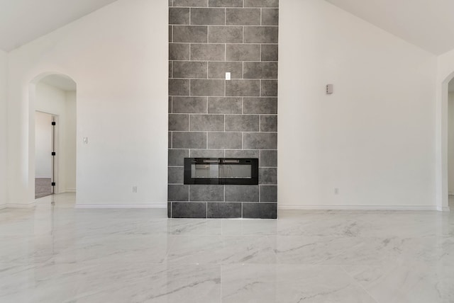 12045 W Palomino Ave, Odessa, TX 79764 - unfurnished living room featuring arched walkways, marble tiled floors, a tile fireplace, and high vaulted ceiling