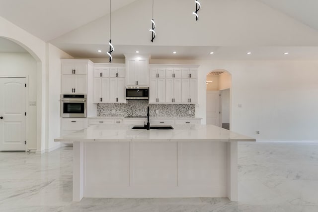 12045 W Palomino Ave, Odessa, TX 79764 - kitchen featuring appliances with stainless steel finishes, light marble finish flooring, a spacious island, tasteful backsplash, and white cabinets