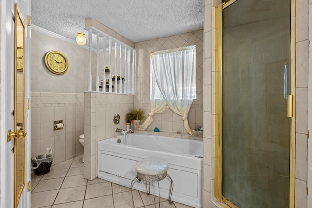 5714 Ector Ave, Odessa, TX 79714 - full bathroom with tile walls, tile patterned flooring, a bath, a textured ceiling, and a stall shower