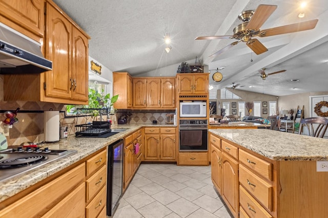 5714 Ector Ave, Odessa, TX 79714 - kitchen featuring oven, wine cooler, under cabinet range hood, vaulted ceiling, and white microwave
