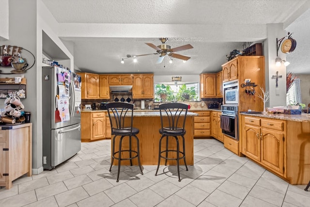 5714 Ector Ave, Odessa, TX 79714 - kitchen featuring stainless steel fridge with ice dispenser, under cabinet range hood, a textured ceiling, a ceiling fan, and decorative backsplash