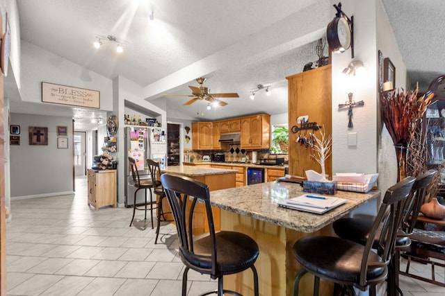 5714 Ector Ave, Odessa, TX 79714 - dining room with track lighting, a textured ceiling, wine cooler, lofted ceiling, and light tile patterned floors