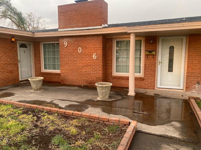 906 S Franklin Ave, Monahans, TX 79756 - entrance to property with a chimney, brick siding, and a patio area