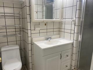 906 S Franklin Ave, Monahans, TX 79756 - full bath featuring tile walls, vanity, toilet, and a stall shower