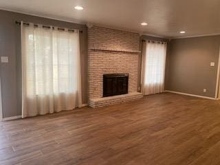 906 S Franklin Ave, Monahans, TX 79756 - unfurnished living room featuring wood finished floors, a fireplace, baseboards, and recessed lighting