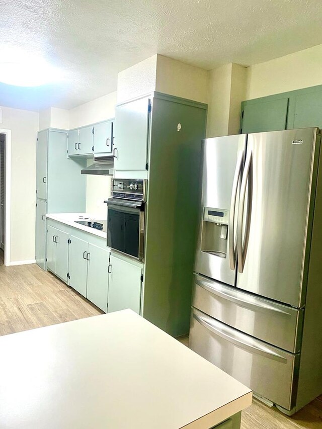906 S Franklin Ave, Monahans, TX 79756 - kitchen featuring black appliances, light wood finished floors, under cabinet range hood, light countertops, and a textured ceiling