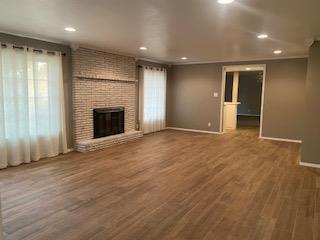906 S Franklin Ave, Monahans, TX 79756 - unfurnished living room featuring baseboards, a brick fireplace, wood finished floors, and recessed lighting