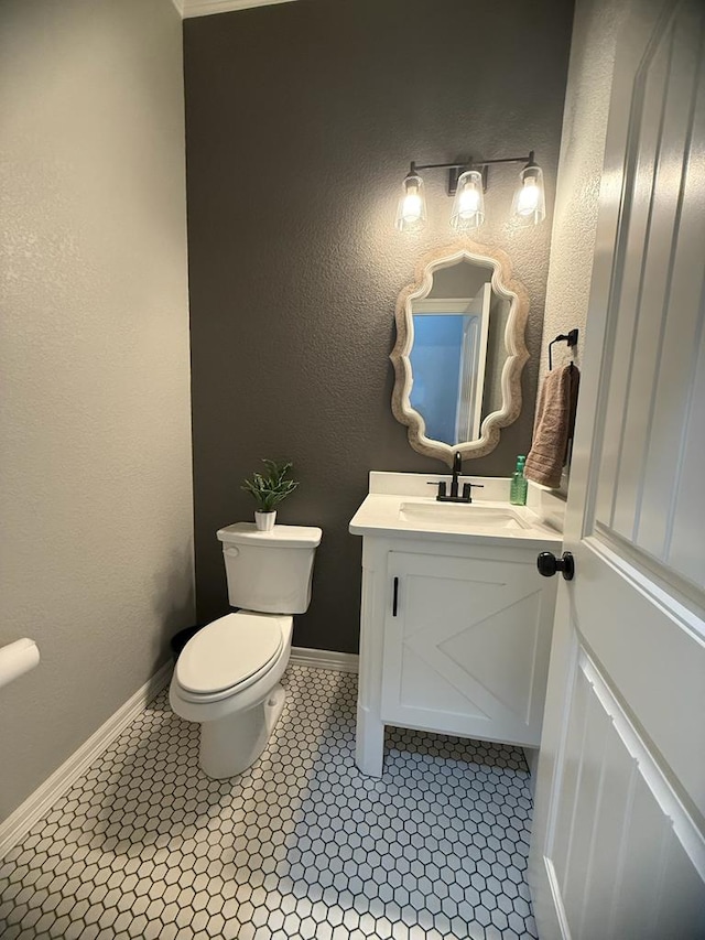 bathroom featuring tile patterned flooring, toilet, baseboards, and vanity