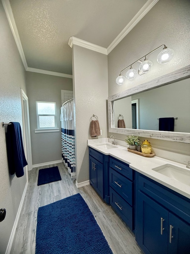 full bathroom featuring double vanity, wood finished floors, a sink, crown molding, and a textured ceiling