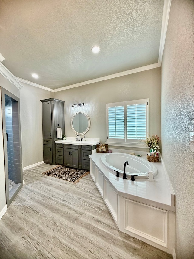 full bath with ornamental molding, vanity, a textured ceiling, and a textured wall
