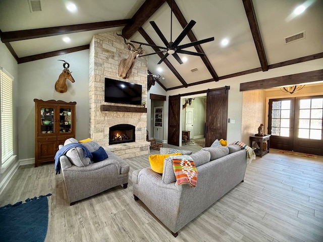 living room with wood finished floors, visible vents, a barn door, and beamed ceiling