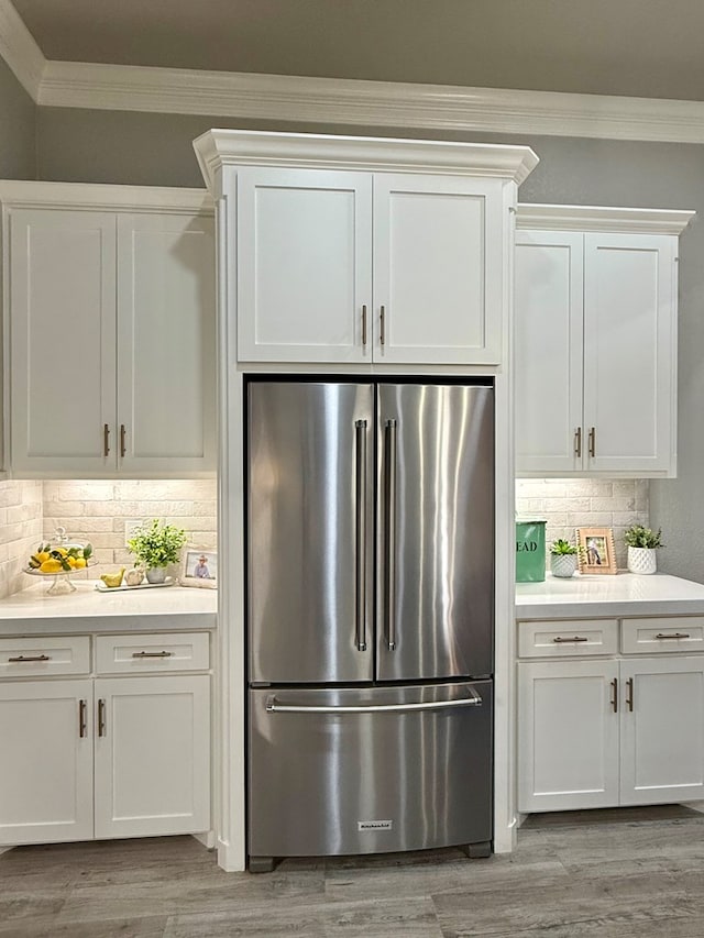 kitchen featuring high quality fridge, ornamental molding, light wood finished floors, backsplash, and light countertops