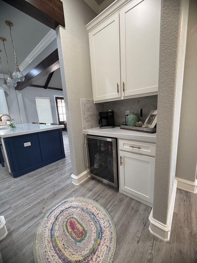 bar with light wood finished floors, beverage cooler, baseboards, decorative backsplash, and ornamental molding