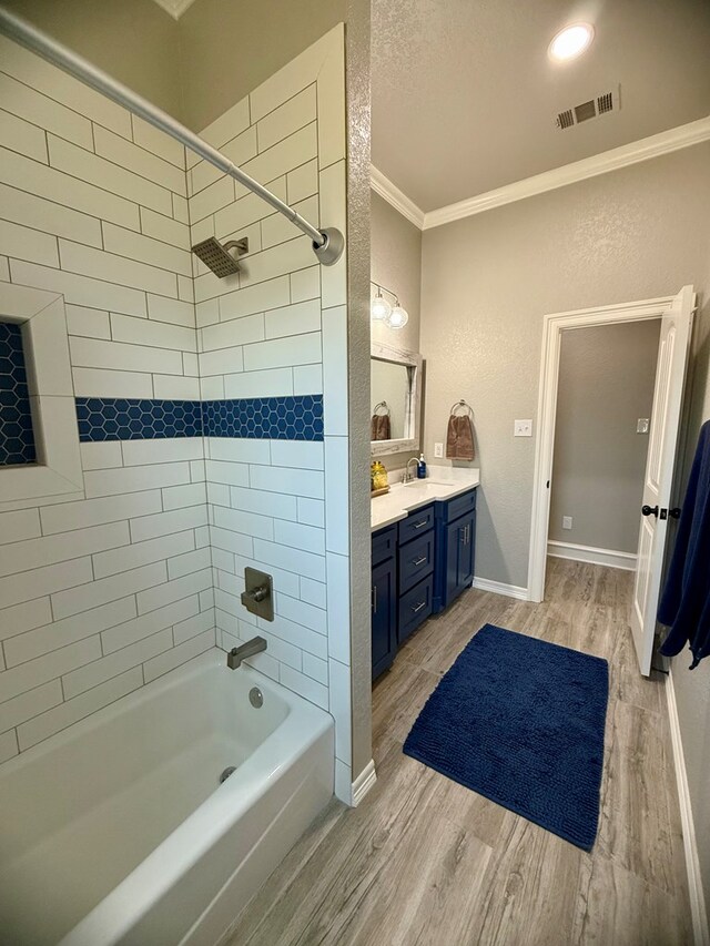 bathroom featuring tub / shower combination, wood finished floors, crown molding, visible vents, and vanity