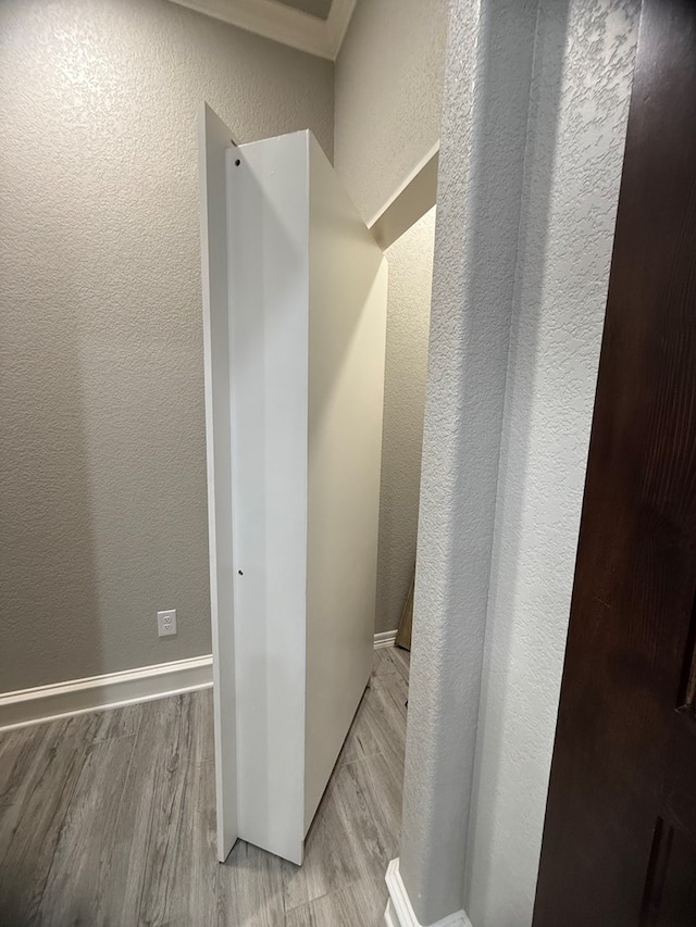 bathroom with a textured wall, baseboards, and wood finished floors