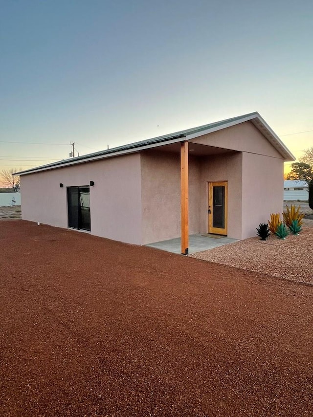 1402 W Philadelphia St, Marfa, TX 79843 - back of house at dusk with stucco siding and a patio area