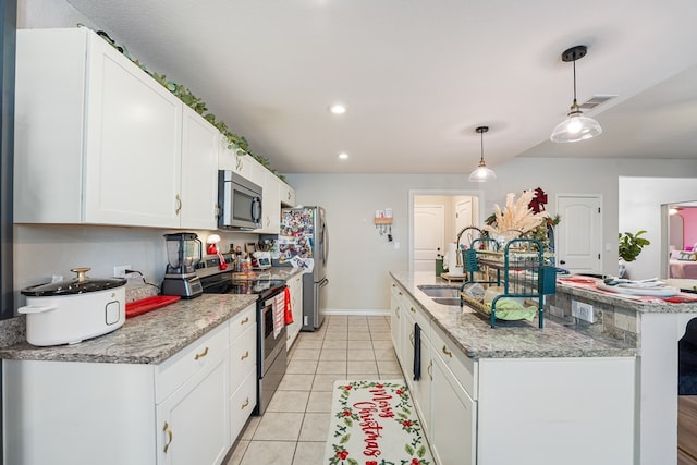 kitchen with white cabinets, light stone counters, decorative light fixtures, light tile patterned floors, and appliances with stainless steel finishes