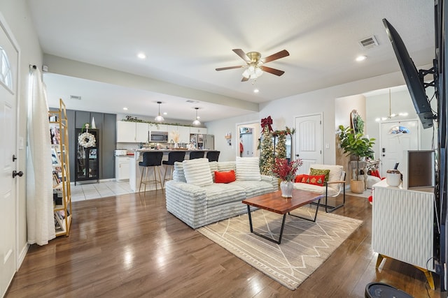 living room with hardwood / wood-style floors and ceiling fan with notable chandelier