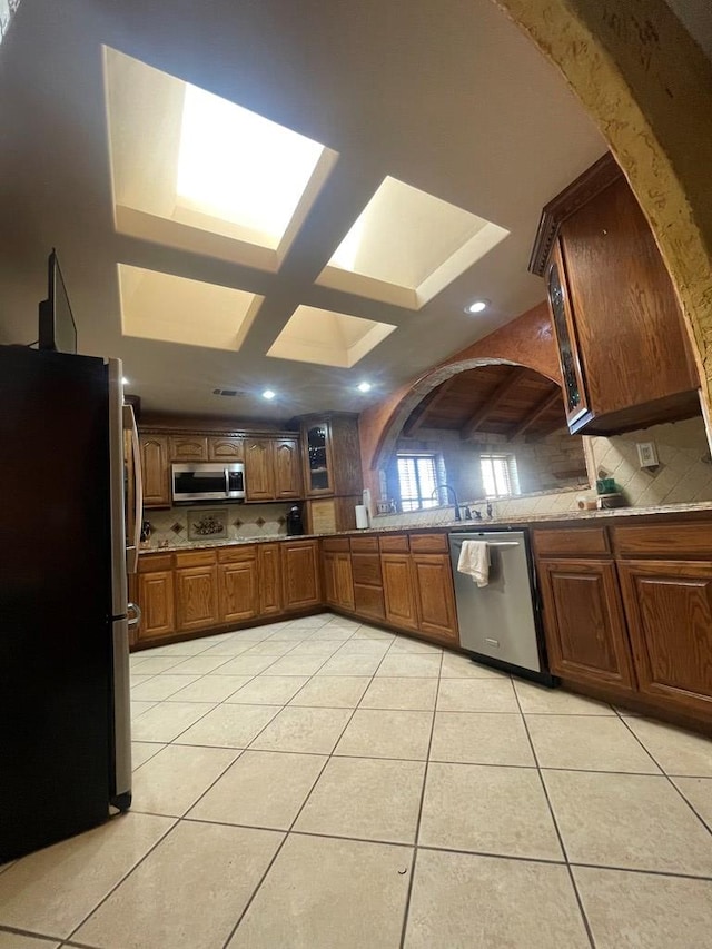 3934 N Bucknell Ave, Odessa, TX 79764 - kitchen featuring appliances with stainless steel finishes, decorative backsplash, light tile patterned floors, glass insert cabinets, and recessed lighting