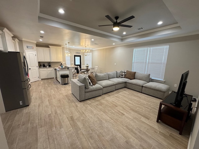 1715 Morgan Way, Midland, TX 79705 - living area featuring a raised ceiling, ceiling fan, light wood finished floors, ornamental molding, and a chandelier
