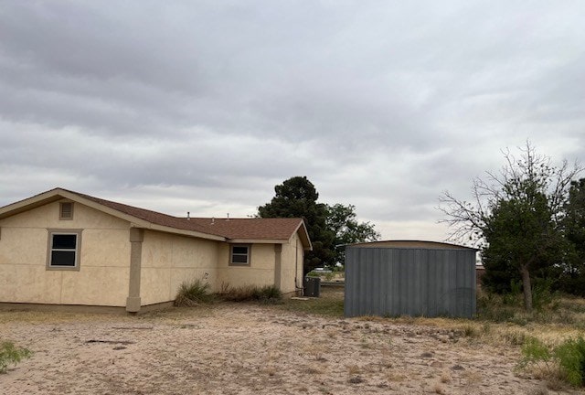 view of home's exterior with stucco siding and an outbuilding
