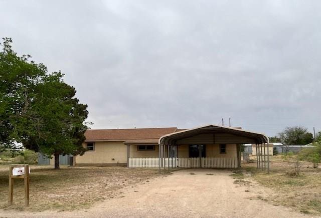 view of front of home with fence, a carport, and driveway