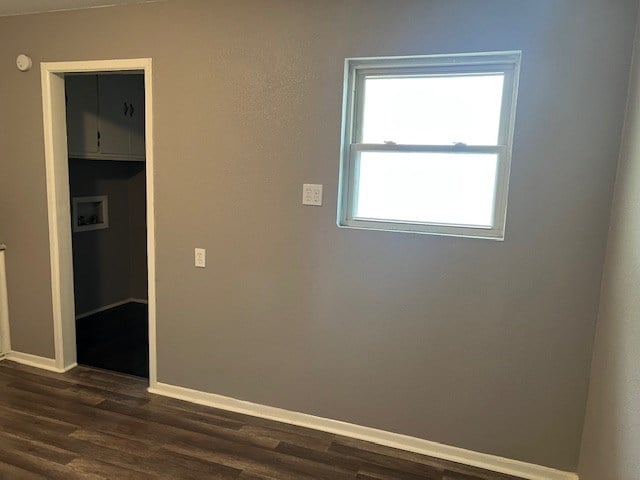 unfurnished room featuring baseboards and dark wood-style flooring