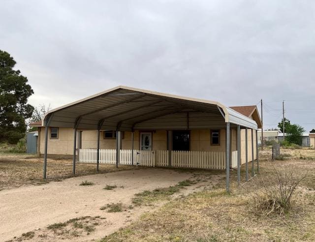 view of vehicle parking with fence, driveway, and a detached carport