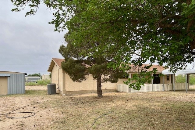 exterior space with fence, an outbuilding, and cooling unit