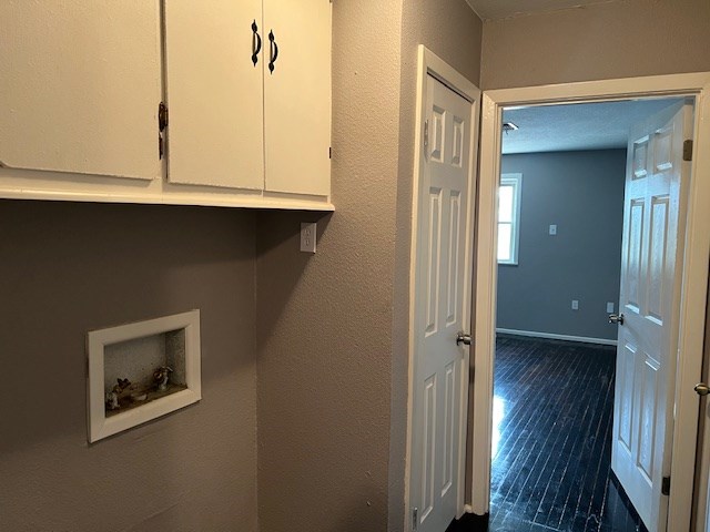 clothes washing area featuring baseboards, hookup for a washing machine, cabinet space, and dark wood-style flooring