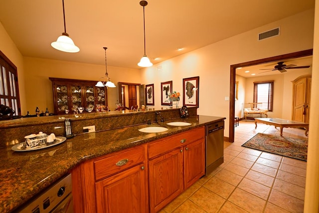 kitchen featuring dishwasher, dark stone counters, hanging light fixtures, ceiling fan, and light tile patterned floors