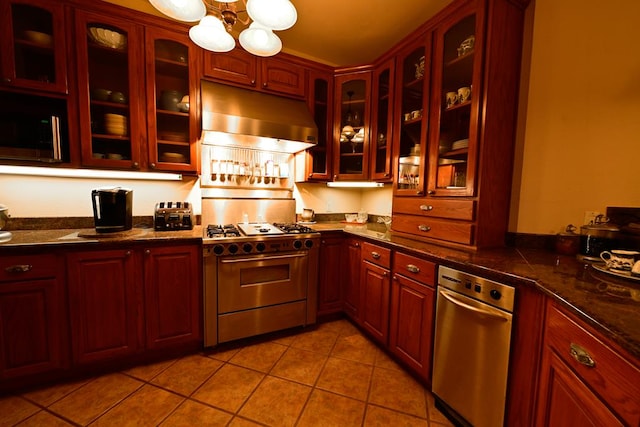 kitchen with ventilation hood, light tile patterned flooring, range with gas stovetop, and dark stone counters