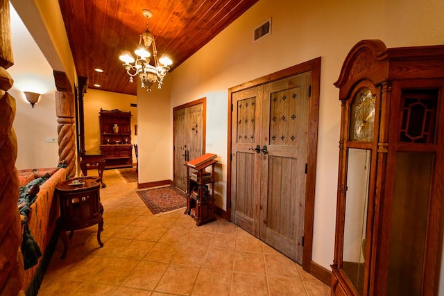 tiled entryway featuring wood ceiling and a chandelier