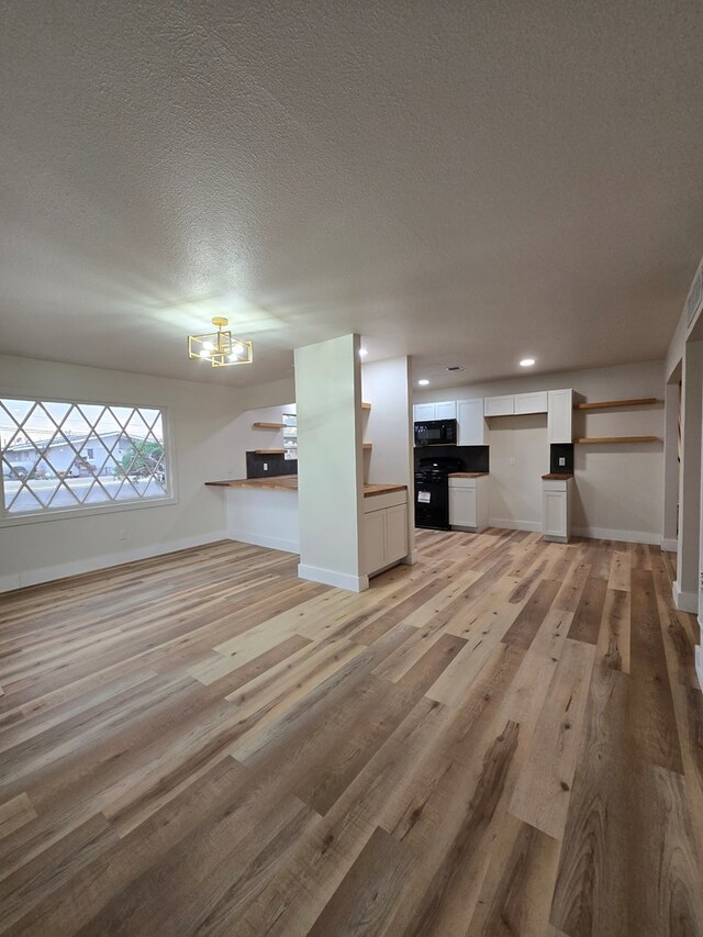 2500 Roper St, Odessa, TX 79761 - unfurnished living room with a chandelier, light wood finished floors, and a textured ceiling