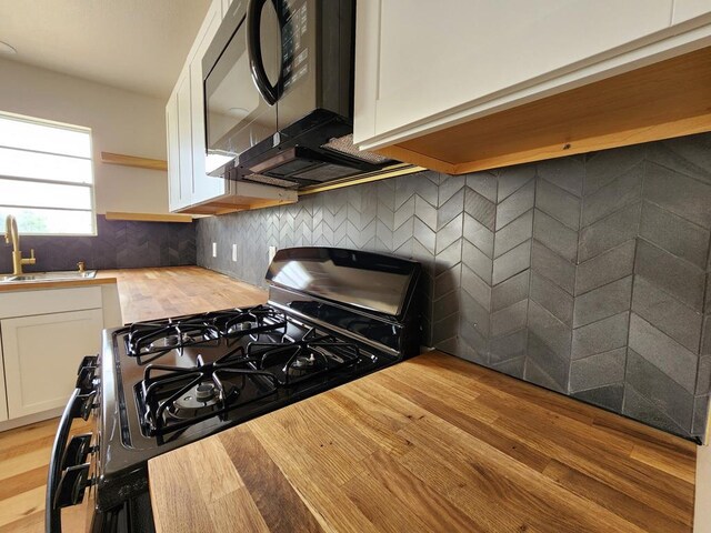2500 Roper St, Odessa, TX 79761 - kitchen with stainless steel gas range, black microwave, white cabinetry, open shelves, and butcher block counters