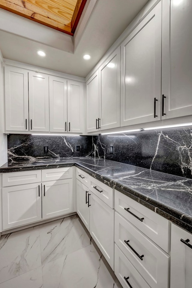 8634 Luz Dr, Odessa, TX 79765 - kitchen with recessed lighting, white cabinetry, tasteful backsplash, light marble finish floors, and dark stone countertops