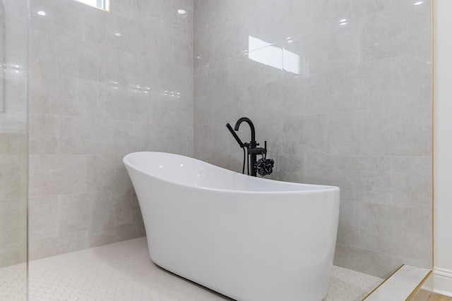 bathroom featuring plus walk in shower, tile patterned floors, and tile walls