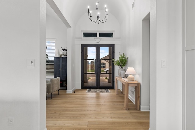 entrance foyer featuring a chandelier, french doors, high vaulted ceiling, and light hardwood / wood-style floors