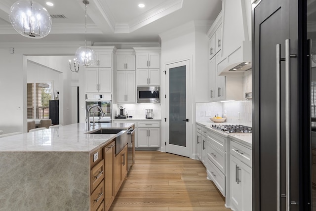 kitchen with appliances with stainless steel finishes, light stone counters, custom exhaust hood, pendant lighting, and white cabinets