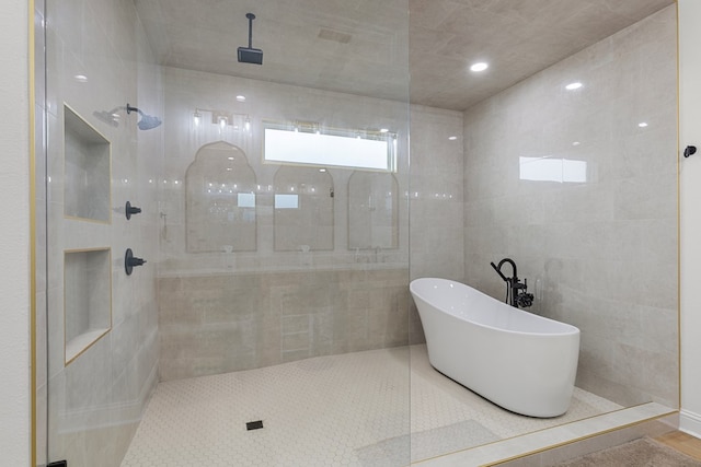 bathroom featuring tile walls and independent shower and bath