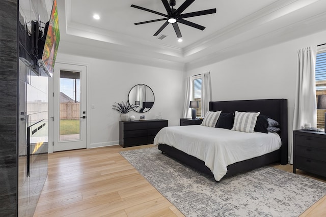 bedroom featuring a raised ceiling, multiple windows, ceiling fan, and light hardwood / wood-style floors