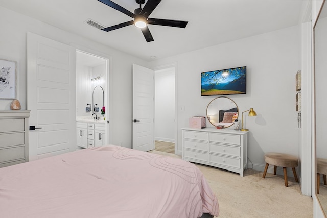 bedroom with ceiling fan, light colored carpet, and ensuite bathroom