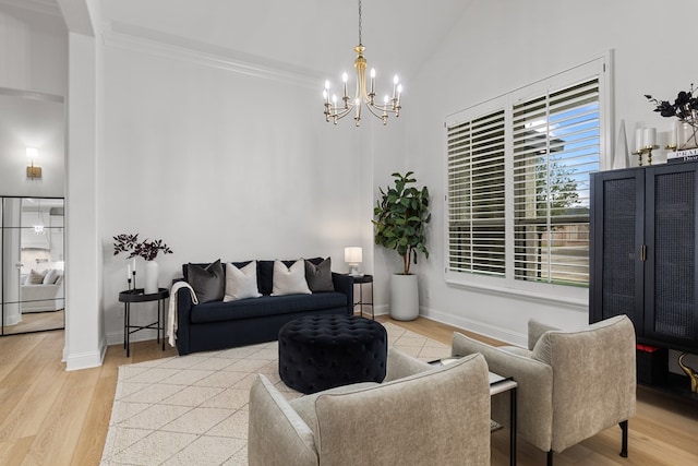 living room with light hardwood / wood-style floors, ornamental molding, high vaulted ceiling, and an inviting chandelier