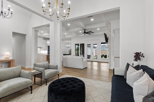 living room with french doors, coffered ceiling, beamed ceiling, ceiling fan with notable chandelier, and light wood-type flooring