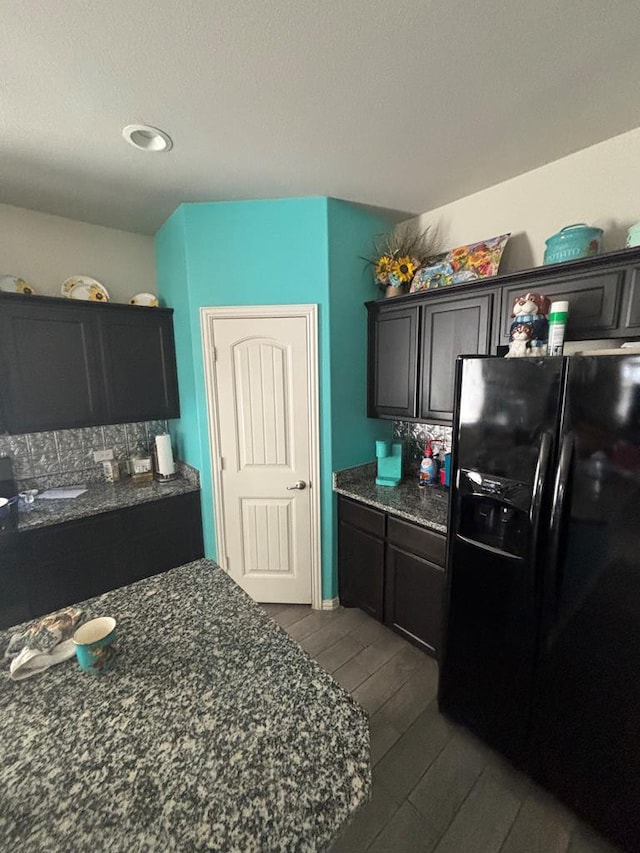 6912 Boss Rnch, Odessa, TX 79765 - kitchen featuring black fridge, wood tiled floors, dark stone counters, tasteful backsplash, and recessed lighting