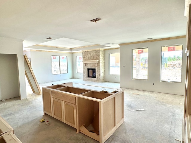 44 La Fauna Dr, Odessa, TX 79765 - kitchen featuring open floor plan, a fireplace, light brown cabinets, concrete floors, and ornamental molding