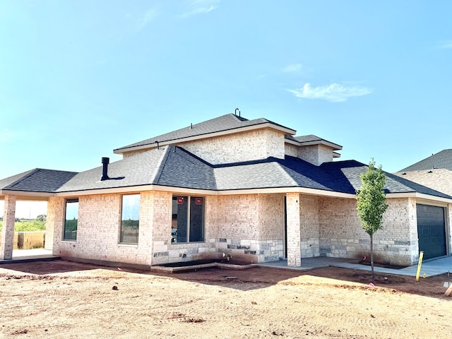 44 La Fauna Dr, Odessa, TX 79765 - back of property featuring roof with shingles, an attached garage, a patio, and brick siding