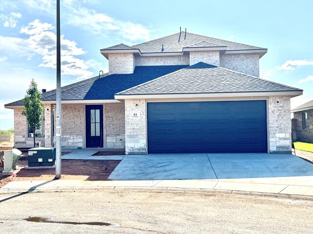 44 La Fauna Dr, Odessa, TX 79765 - view of front of property with an attached garage, driveway, roof with shingles, brick siding, and stone siding